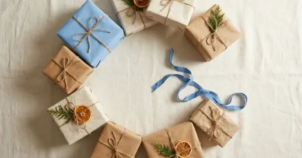 Overhead flat-lay of mismatched kraft and blue wrapped gifts arranged in a circle with one empty spot and a tangled blue ribbon